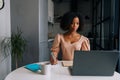 Portrait of focused African-American female student sitting at desk serious looking at screen making notes studying Royalty Free Stock Photo