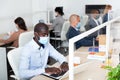 Focused afro american businessman in medical mask working in office