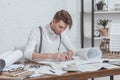 portrait of focused architect working on sketches at workplace