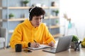 Focused asian man working on laptop and writing Royalty Free Stock Photo