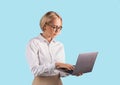 Portrait of focused businesswoman using laptop computer over blue studio background