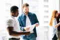 Portrait of focused Caucasian office employee worker reporting to dissatisfied black boss about project with financial