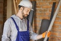 Portrait of focused male builder wearing overalls and hard hat holding a metal stud for drywall on interior site