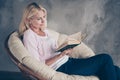 Portrait of focused middle aged woman in pastel color pullover denim jeans read book encyclopedia want know more have