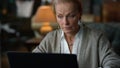 Portrait focused old woman working laptop computer in vintage living room.