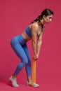 Girl doing resistance band deadlifts on maroon background