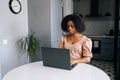 Portrait of focused young African American woman working or studying remotely from home office using laptop siting at Royalty Free Stock Photo