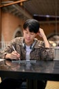 Portrait of a focused young Asian man taking notes on a digital tablet, remote working at the cafe Royalty Free Stock Photo