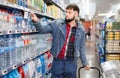 Portrait of focused young man purchasing bottled water in grocery store