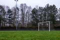 A portrait of a football goal on a grass field on a cloudy and rainy day