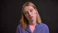 Portrait of formally-dressed tired woman watching into camera with passivity on black background.