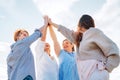 Portrait of four cheerful laughing women holding hands Up making High Five during outdoor walking. They looking at the camera.