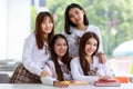 Portrait of four cute and young Asian girl group, wearing Japanese, Korean style schoolgirl uniform, sitting pose smile to camera