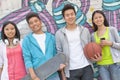 Portrait of four friends holding a skateboard and soccer ball hanging out in front of a wall covered in graffiti Royalty Free Stock Photo