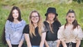 Portrait of four girlfriends schoolgirls sitting on the grass.