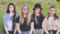 Portrait of four girlfriends schoolgirls sitting on the grass.