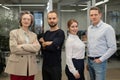 Portrait of four office workers. A gray-haired mature woman, a Caucasian man, a bearded man and a red-haired woman cross