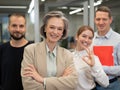 Portrait of four office workers. A gray-haired mature woman, a Caucasian man, a bearded man and a red-haired woman.