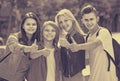 Portrait of four teenagers standing and holding thumbs up togeth