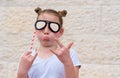 Funny little girl with paper glasses carnival mask having fun on white wall background.