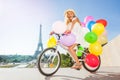 Happy French girl cycling with colorful balloons