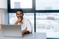 Portrait of friendly black male freelancer using laptop computer and smiling looking at camera while enjoying work Royalty Free Stock Photo