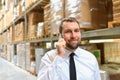 portrait friendly businessman manager in suit on the phone in the warehouse of a company