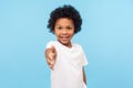 Portrait of friendly cheerful little boy with curly hair in white T-shirt giving hand to handshake and smiling at camera Royalty Free Stock Photo