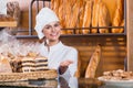 Portrait of friendly young woman at bakery display