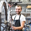 Portrait of a friendly and competent bicycle mechanic in a works