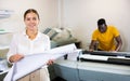 Portrait of friendly female employee of printing house with stack of notebooks in her hands Royalty Free Stock Photo