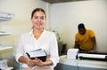 Portrait of friendly female employee of printing house with stack of notebooks in her hands Royalty Free Stock Photo