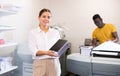 Portrait of friendly female employee of printing house with stack of notebooks in her hands Royalty Free Stock Photo