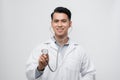 Portrait of a friendly handsome male doctor dressed in uniform holding stethoscope and looking at camera isolated over white Royalty Free Stock Photo