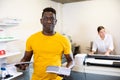 Portrait of friendly male employee of printing house with stack of notebooks in her hands