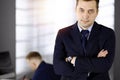 Portrait of a friendly middle aged businessman with crossed arms, while standing in a sunny office. Business concept Royalty Free Stock Photo