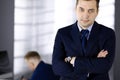 Portrait of a friendly middle aged businessman in a dark blue suit, with crossed arms, while standing in an office Royalty Free Stock Photo