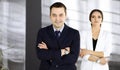 Portrait of a friendly middle aged businessman in a dark blue suit, standing with crossed arms together with a colleague Royalty Free Stock Photo