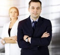 Portrait of a friendly middle aged businessman in a dark blue suit, standing with crossed arms together with a colleague Royalty Free Stock Photo