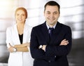 Portrait of a friendly middle aged businessman in a dark blue suit, standing with crossed arms together with a colleague Royalty Free Stock Photo