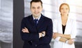 Portrait of a friendly middle aged businessman in a dark blue suit, standing with crossed arms together with a colleague Royalty Free Stock Photo