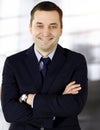 Portrait of a friendly middle aged businessman in a dark blue suit, standing with crossed arms together with a colleague Royalty Free Stock Photo