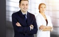 Portrait of a friendly middle aged businessman in a dark blue suit, standing with crossed arms together with a colleague Royalty Free Stock Photo