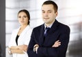 Portrait of a friendly middle aged businessman in a dark blue suit, standing with crossed arms together with a colleague Royalty Free Stock Photo