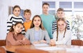 Portrait of positive group of pupils with female teacher sitting in schoolroom