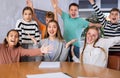 Portrait of positive group of pupils with female teacher sitting in schoolroom