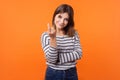 Portrait of friendly pretty young woman with brown hair in long sleeve striped shirt. indoor studio shot isolated on orange
