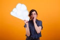 Portrait of friendly shocked woman with thought clound in her hand over yellow background in studio