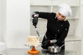 Portrait of friendly smiling female professional confectioner topping a cupcake with cream using a pastry bag Royalty Free Stock Photo