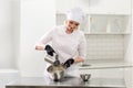 Portrait of friendly smiling female professional confectioner topping a cupcake with cream using a pastry bag Royalty Free Stock Photo